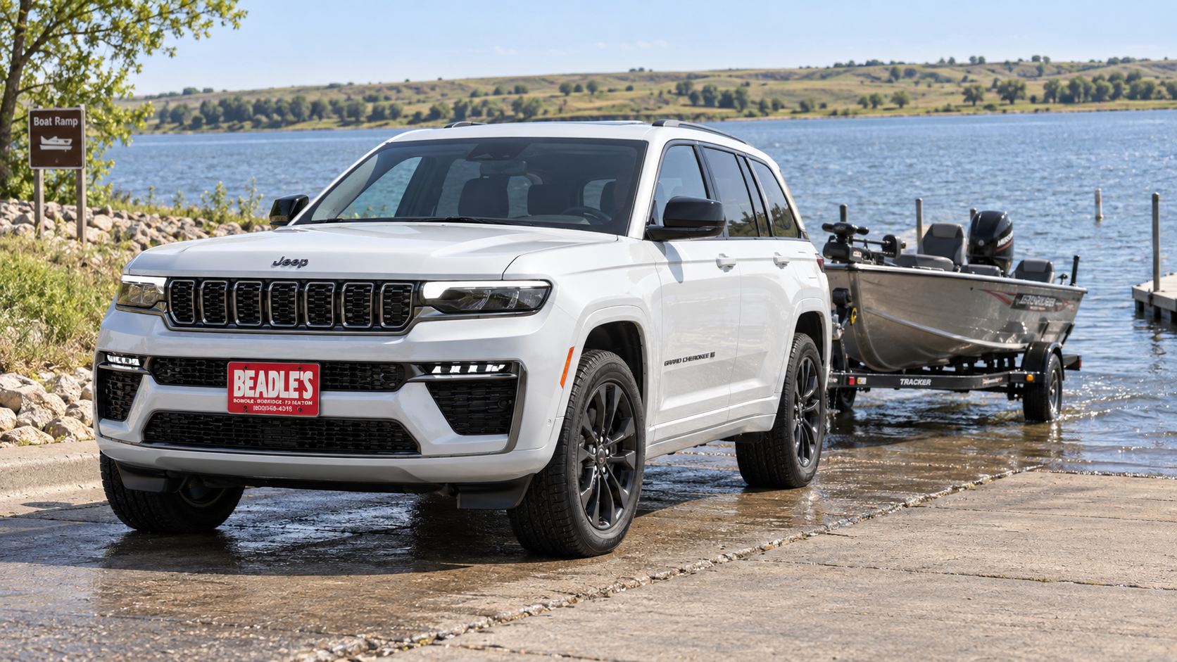 2026 Jeep Grand Cherokee towing a boat at a South Dakota lake, at Beadle's Chrysler Center